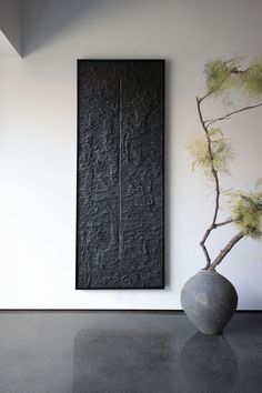 a vase sitting in front of a painting on the wall next to a tree branch