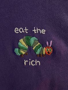 the very hungry caterpillar embroidered onto a purple t - shirt that says eat the rich