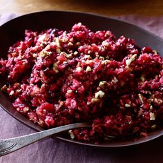 a bowl filled with beet and nuts on top of a table next to a spoon