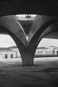 black and white photograph of an underpass with buildings in the background, taken from below