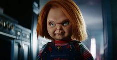 a doll with red hair and blue eyes standing in front of a stove top oven