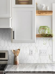 a kitchen with white cabinets and wooden utensils sitting on the counter next to an oven