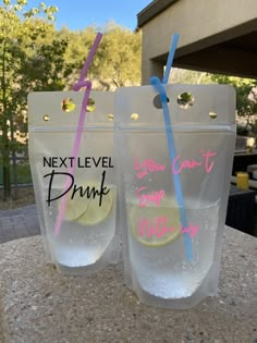 two plastic cups with straws and lemon in them