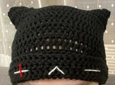 a child wearing a black crocheted cat hat