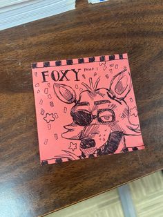 a piece of paper with a drawing of a fox on it sitting on top of a wooden table