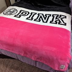 a pink and black blanket sitting on top of a bed