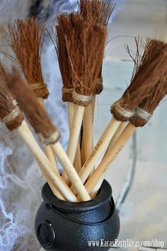 four brown brooms in a black vase on a table