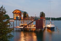 a boat dock with two boats and a house on it's deck at night