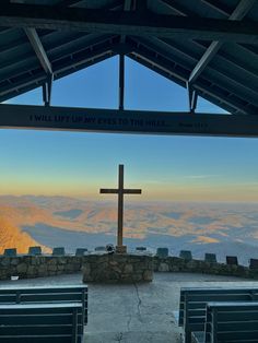 a cross on top of a hill with mountains in the background