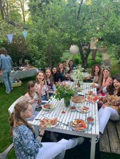 a group of people sitting around a table eating food and drinking watermelon juice