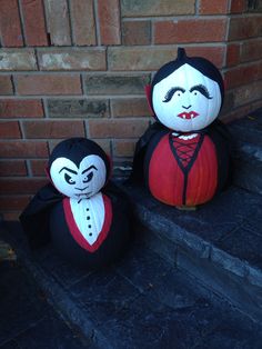 two stuffed dracula dolls sitting on the steps next to a brick wall, one is black and red