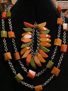 For Sale is a rare 1930's Deco Bakelite Suite. The necklace has 22 Bakelite Faceted Multi Color Cubes on a Brass Chain. It measures 29" can be wrapped as double chain necklace. The bracelet has 20 multi color Bakelite slices that hang individually like a charm bracelet. The earrings are clip-on. They measure 1.5 inches. This suite is in excellent condition. The colors are orange, green and mustard. Luxury Vintage Bakelite Jewelry, Bakelite Jewelry, Bakelite Bangles, Double Chain Necklace, The 20s, Vintage Bakelite, Double Chain, Classic Cartoons, Retro Mid Century