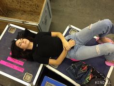 a young woman laying on top of a pile of luggage next to a pink suitcase