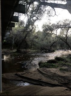 a river running under a bridge next to trees