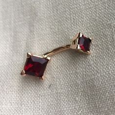 a pair of red earrings sitting on top of a white cloth