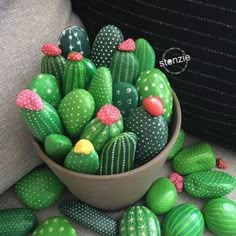 a bowl filled with lots of green and pink cactus decorations on top of a couch