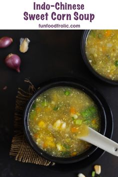 two black bowls filled with soup on top of a table next to garlic and onions