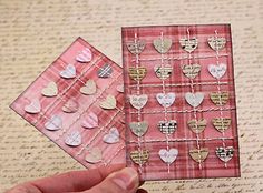 two pieces of paper with hearts attached to them are being held by someone's hand