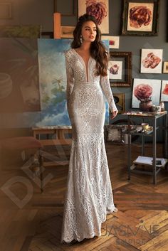 a woman in a white wedding dress standing on a wooden floor with paintings behind her