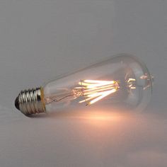 an old fashioned light bulb on a white surface with the light coming from it's side