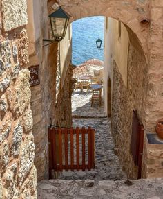 an alley way with stone walls and wooden gates leading to the water's edge