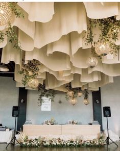 the ceiling is decorated with hanging lights and greenery for an elegant wedding reception at this venue