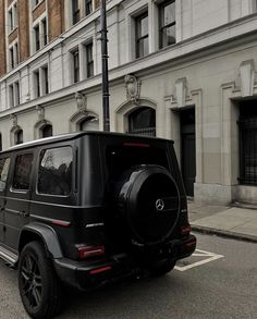 a black mercedes g - class is parked on the street