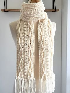 a white crocheted scarf hanging from a hook on a mannequin's dummy