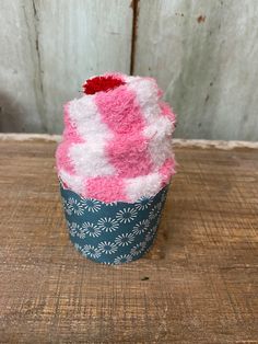 a pink and white cupcake sitting on top of a wooden table