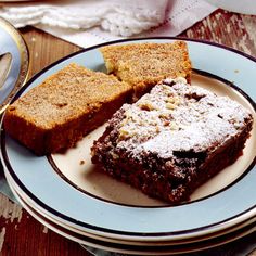 three pieces of brownie on a plate next to a cup and saucer filled with powdered sugar