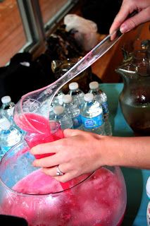 a person is cutting into a pink substance in a bowl with water bottles behind it