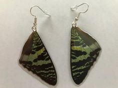 a pair of green and black butterfly shaped earrings on white surface with silver earwires