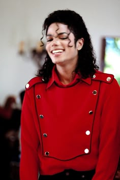 a man with long black hair wearing a red jacket and white polka dot eyeshadow