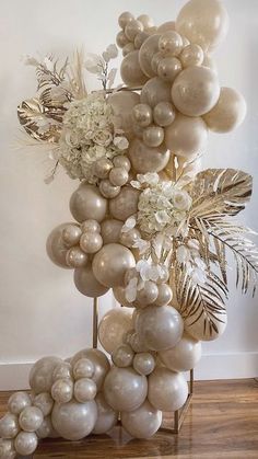 a bunch of balloons that are on top of a metal stand with white flowers and greenery