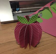 an apple shaped origami sitting on top of a wooden table