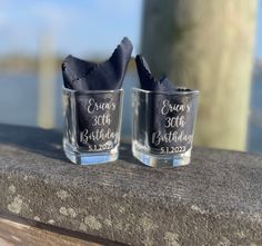 two shot glasses sitting on top of a wooden table next to each other with the words cheers 30th birthday written on them