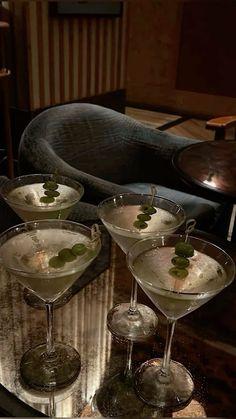 three martini glasses filled with white wine and garnished with green leaves