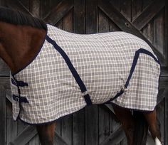 a horse wearing a blanket standing in front of a wooden fence with it's head down