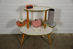 three tiered table with two vases on top and one shelf holding other items