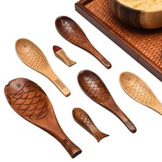 wooden spoons and bowls with fish designs are on a tray next to a bowl