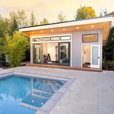 a small pool house with a large swimming pool in the middle and an outdoor gym