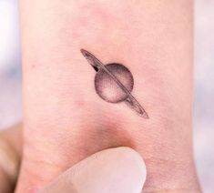 a small saturn tattoo on the ankle