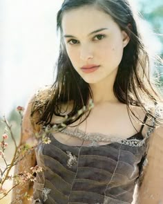 a beautiful young woman standing next to a tree