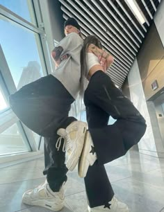 two people are posing for the camera in front of an airport window with their hands on their hipss