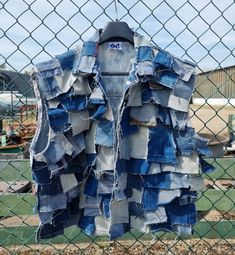 an old jean jacket hanging on a chain link fence in front of a construction site