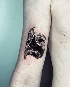 a man's arm with a black mask tattoo on it