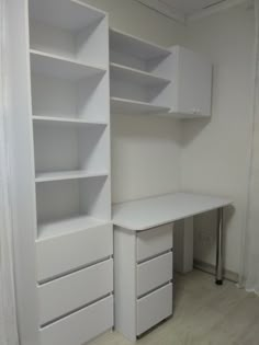 an empty white desk and shelves in a room