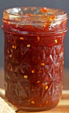 a jar filled with jam sitting on top of a wooden cutting board