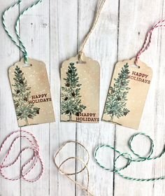 three tags with the words happy holidays hanging from twine on a white wooden background