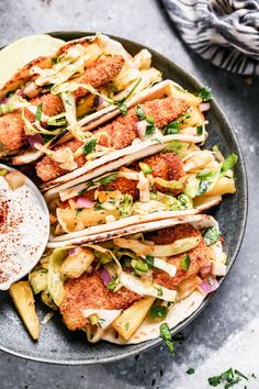 a plate filled with tacos and sauce on top of a table next to a spoon